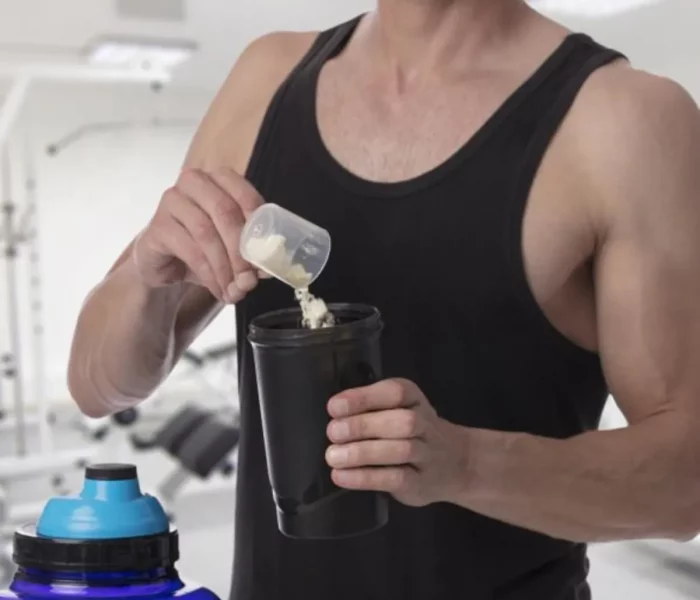 Chico echando creatina en bote para mezclar